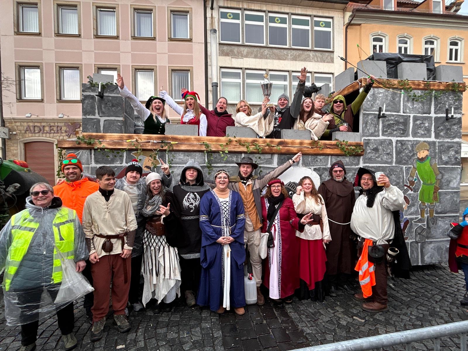 Die ganze Gruppe in Rittergewandung vor dem Wagen mit Pokal